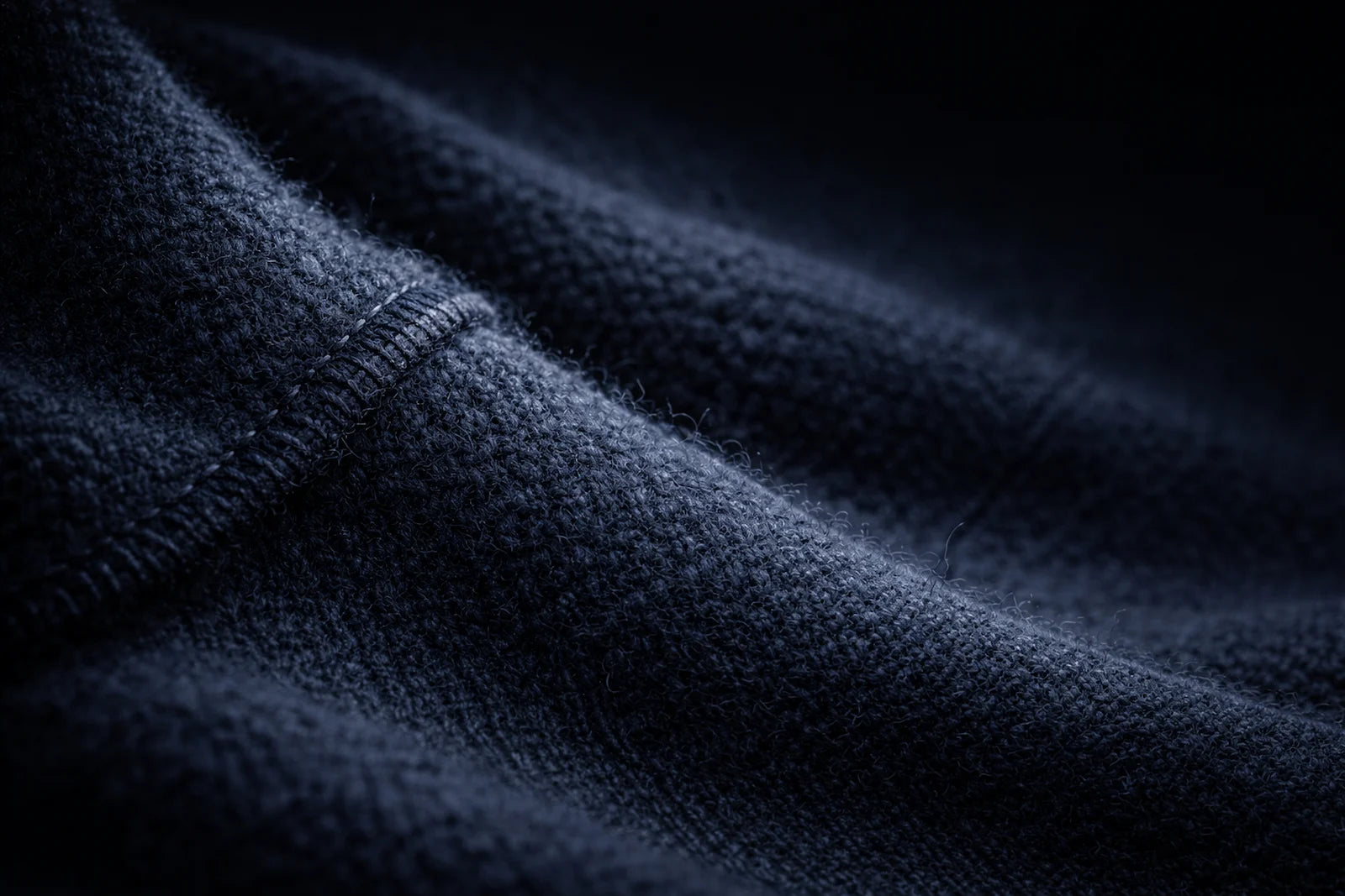 Macro texture of YALKO technical merino wool fabric showing dense knit fibers and seam construction